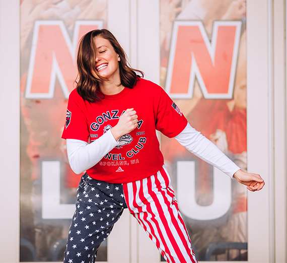 A woman with blond hair hands a Christmas stocking to a woman with long brown hair